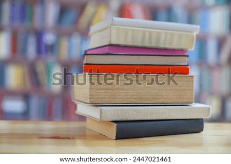 stack of books on wooden table in library background