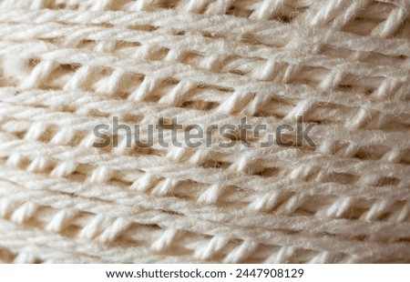 Close-up of a skein of natural cotton light yarn for hand knitting or crocheting. The texture of cotton threads wound into a ball. Textile background. Flat lay, macro, top view, mock up, blank