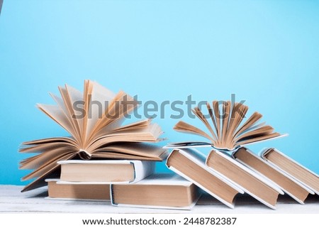 Open books, hardback colorful books on wooden table. blue background. Back to school. Copy space for text. Education business concept