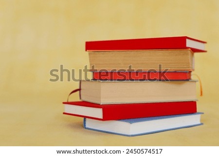 stack of books on wooden table against blurred wall