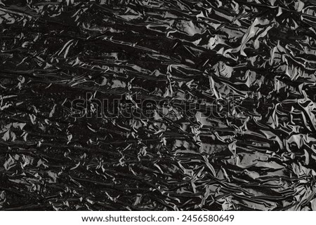 black packaging film with folds and wrinkles, abstract background