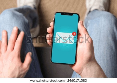 Man received message on mobile phone indoors, top view. Envelope illustration on device screen
