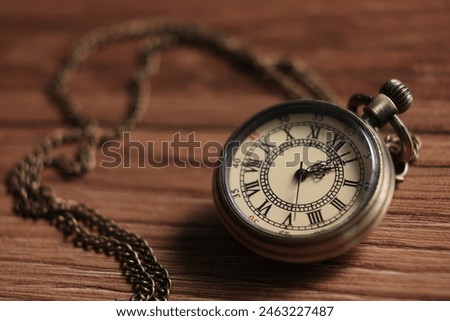 Pocket clock with chain on wooden table, closeup