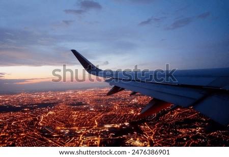 Wing of modern aircraft flying above Paris at night