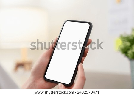 Hand holding smartphone mockup of blank screen for graphic display montage.