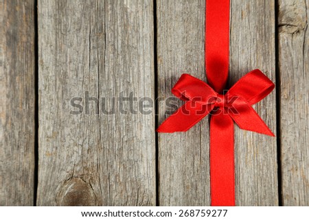 Red ribbon with bow on grey wooden background