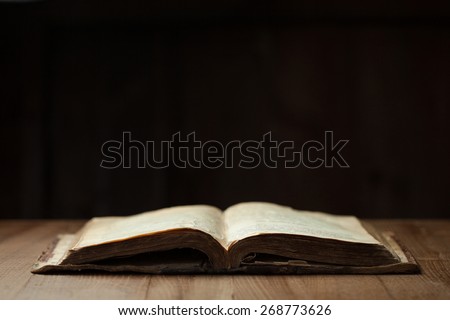 Image of an old Holy Bible on wooden background in a dark space