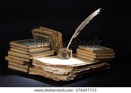 Old fountain pen, books and inkwell on a black textured background