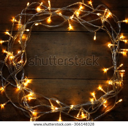 abstract photo of Christmas warm gold garland lights on wooden rustic background. filtered image
