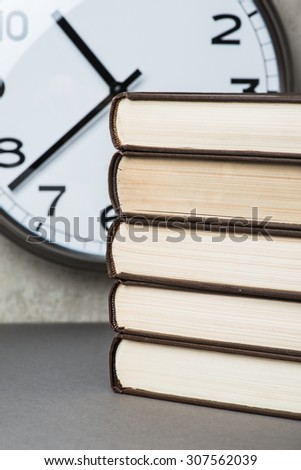 Stack of vintage books over the wall with clock