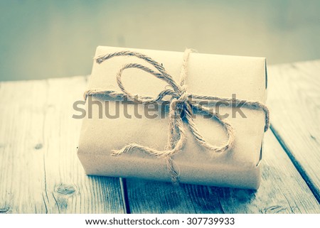 Vintage gift box brown paper wrapped with rope on wood background , vintage tone