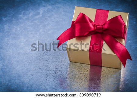 Wrapped golden present with red ribbon bow horizontal view.
