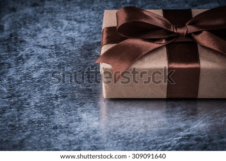 Gift box with ribbon on scratched metallic background holidays concept.
