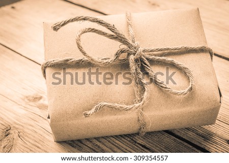 Vintage gift box brown paper wrapped with rope on wood background , antique tone