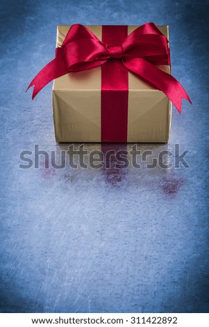 Boxed present with red ribbon on metallic background holiday concept.