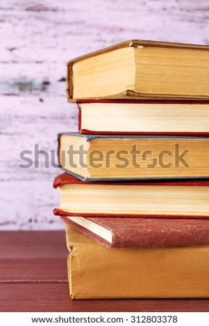 Stack of books on wooden table on pink wooden wall background