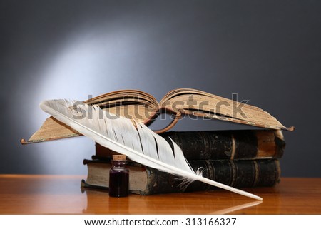 Literature concept. Still life with quill pen near book on wooden table