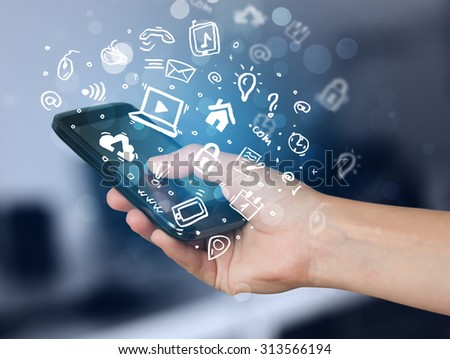 Hand holding smartphone with media icons and symbol collection