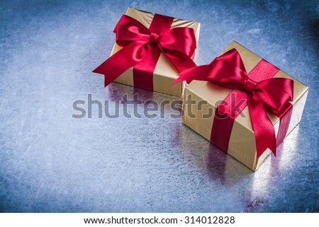 Present box with red ribbon on metallic background.