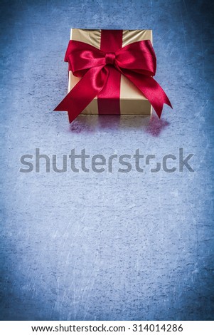 Present box with red ribbon on metallic background holiday concept.