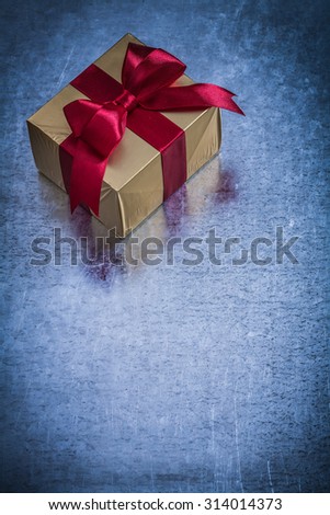 Gift box wrapped in shining golden paper on metallic surface.