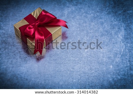 Giftbox wrapped in glittery golden paper on metallic surface copyspace.