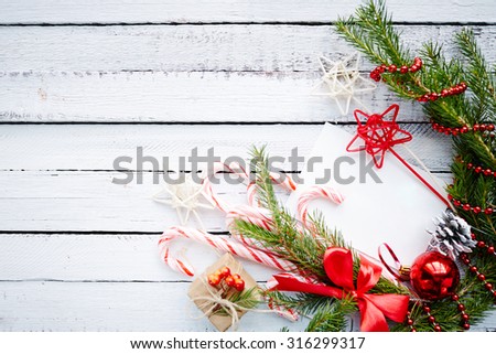 Composition of conifer branches, cones, decorative bubble, stars, beads, candy canes and small giftbox on wooden background