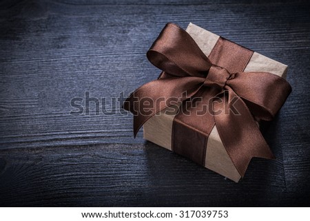 Boxed present with brown bow on vintage wood board copyspace.