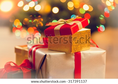 Toned photo of pile of gift boxes against Christmas lights