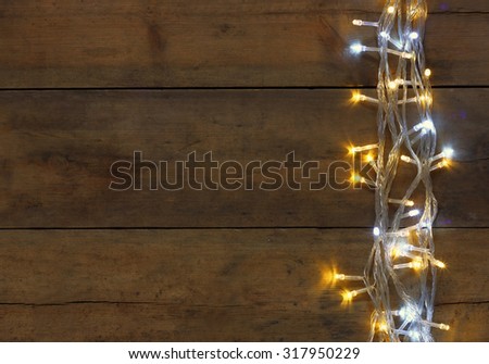 Christmas warm gold garland lights on wooden rustic background. filtered image
