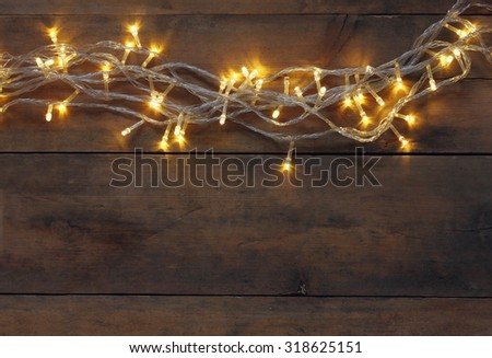 Christmas warm gold garland lights on wooden rustic background. filtered image
