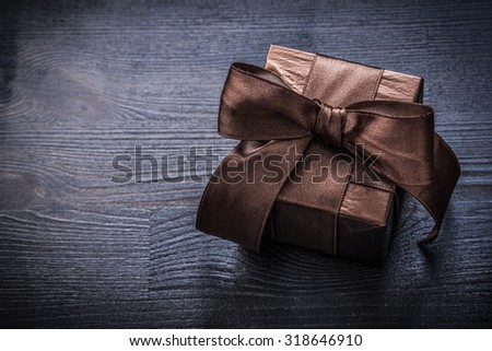 Wrapped giftbox shining paper on vintage wooden board holiday concept.