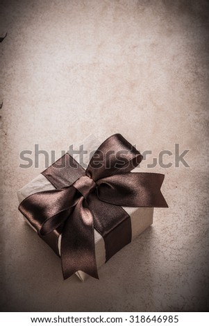 Wrapped giftbox with tied ribbon paper on vintage background.