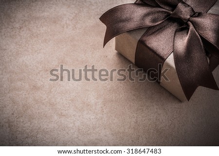 Gift box with tied brown bow paper on vintage background.