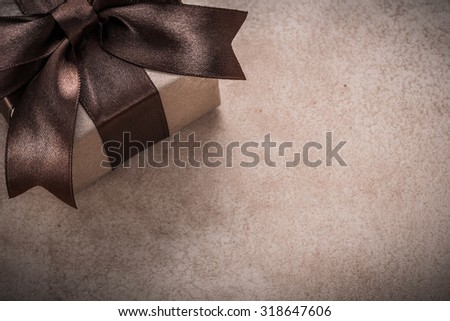 Giftbox with tied brown bow paper on vintage background.