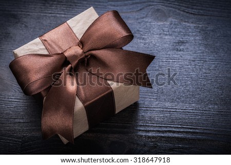 Boxed present tied bow on wood board close up view.