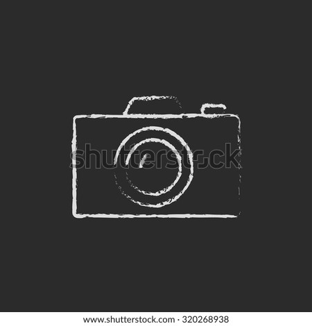 Camera hand drawn in chalk on a blackboard vector white icon isolated on a black background.
