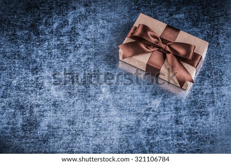 Present box with ribbon on scratched metallic background holidays concept.