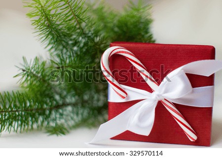 nicely wrapped christmas present decorated with candy cane and christmas tree branch