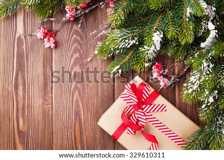 Christmas wooden background with snow fir tree and gift box. View with copy space