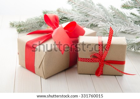 Gifts in kraft paper with a red ribbon for Christmas on a wooden white background.
