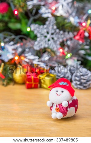Santa doll and christmas tree with gift box decorations on wooden background.