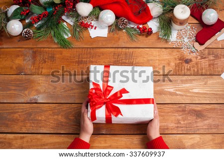 The wooden table with Christmas decorations with hands with gift. Christmas concept