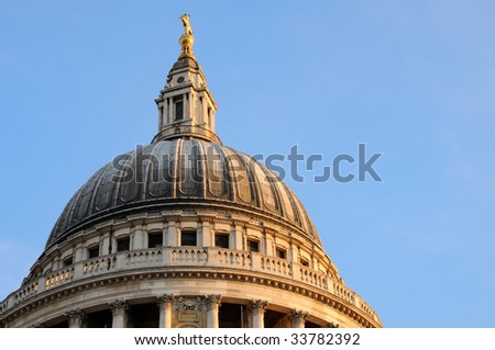 Closeup view of St. Paul's cathedral dome with sidelight by dusk sun and blue sky on background.
