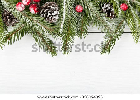 Christmas fir branch with fir cones and red berries on wooden light background