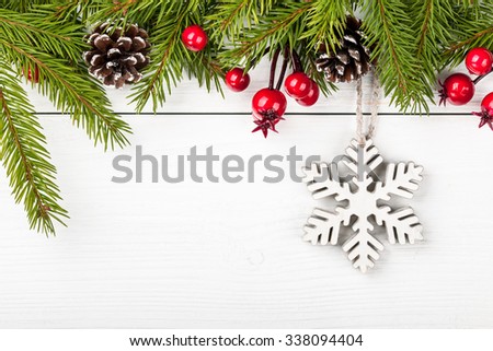 Christmas fir decorated and decorative snowflake on light wooden background