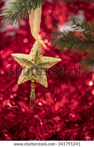Christmas star ornament hang on Christmas tree branch with red bokeh background