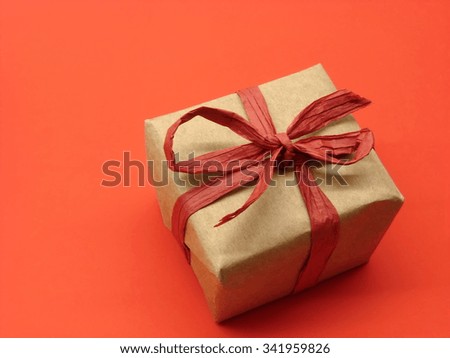 gift package wrapped in gray paper with organic red ribbon on red background