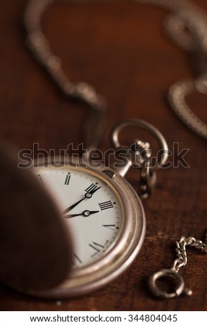 silver turnip pocket watch part with open cover and chain on wooden table