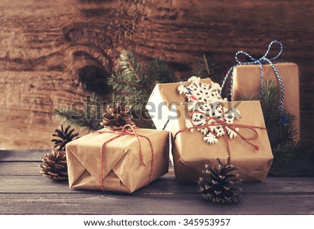 Festive Gifts Decorated with Color Cord, Cinnamon, Pine cones,  Snowflakes , Coniferous on Old Wooden Background. Selective Focus.Toned Image.